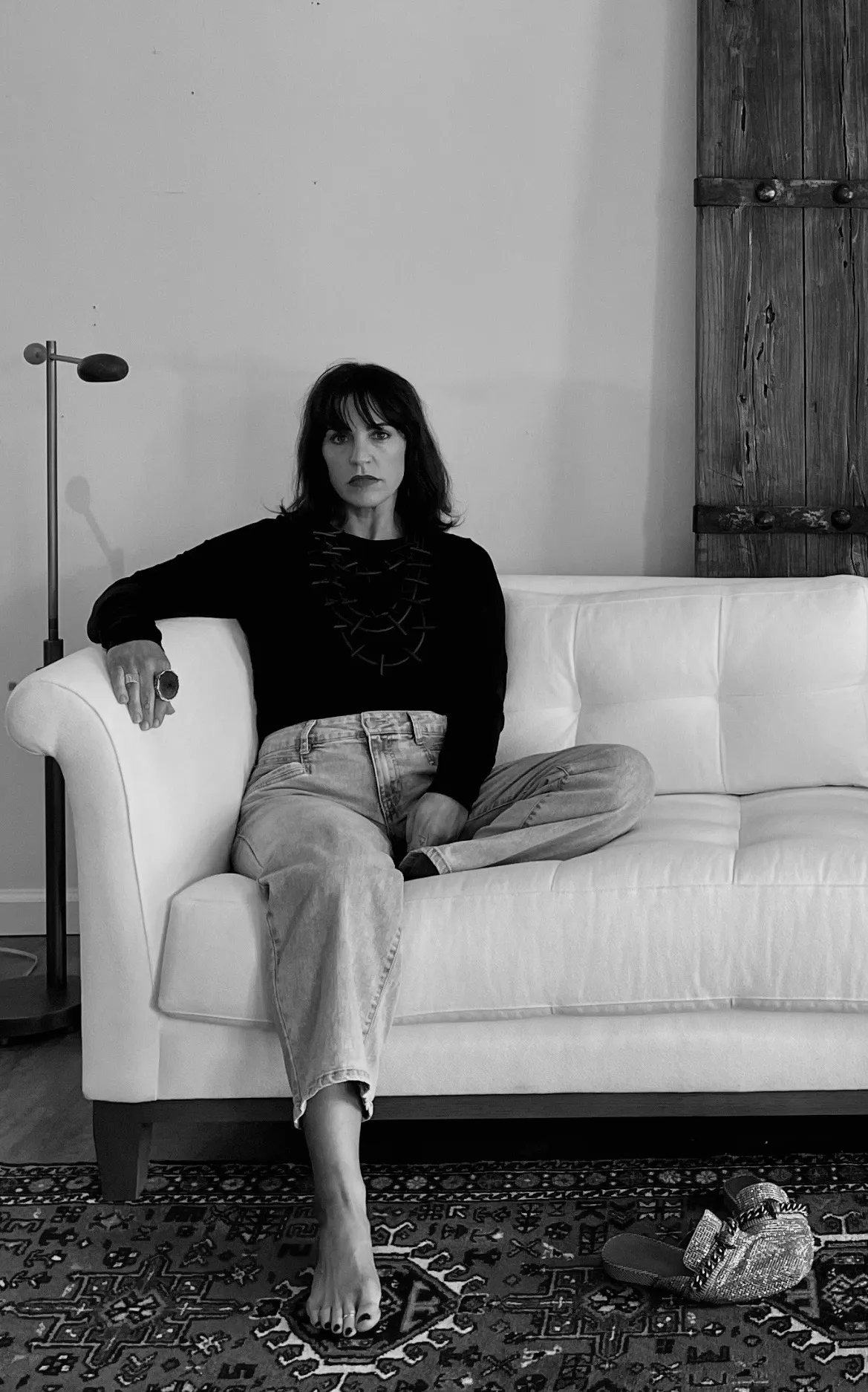 Woman sitting on white sofa, black and white.