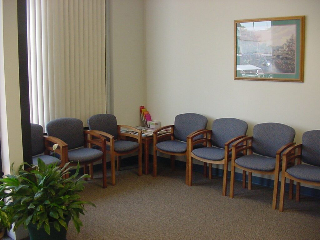 Waiting room with chairs and a plant.